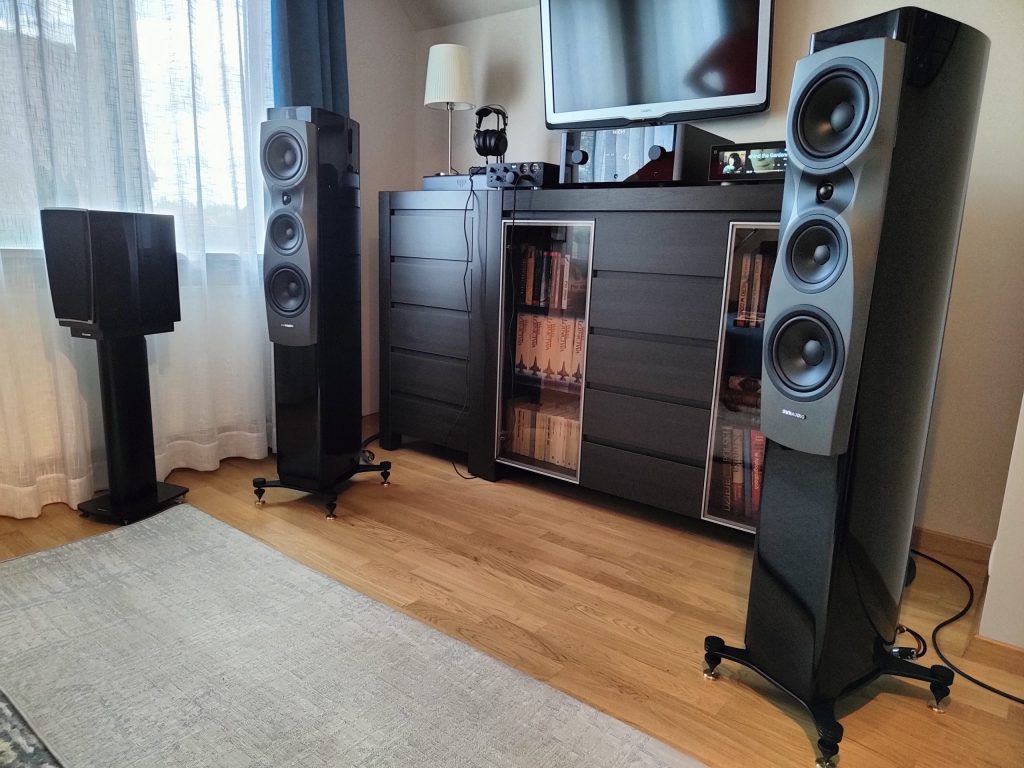 Kolumny podłogowe Dynaudio Confidence w salonie z biblioteką